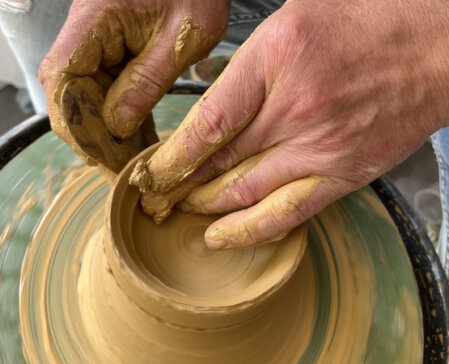 Hand formt eine Keramikschale auf der Töpferscheibe